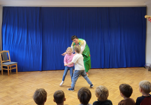 Dziewczynka z chłopcem wykonują zadanie klauna - tańczą w parze.