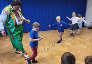 Kilkoro dzieci idzie po linie rozłożonej na podłodze.