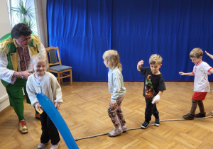 Kilkoro dzieci idzie po linie rozłożonej na podłodze.