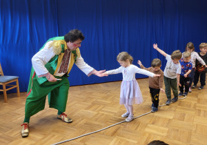 Kilkoro dzieci idzie po linie rozłożonej na podłodze.