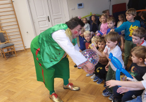 Dzieci rzucają piłką do celu - koło zrobione z rąk klauna.