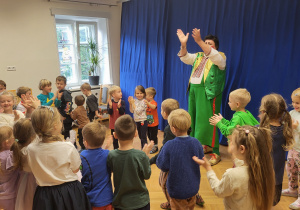 Dzieci bawią się z klaunem w kole - klaszczą w ręce.