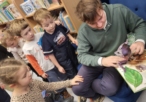 Pan bibliotekarz pokazuje dzieciom trójwymiarową książkę.
