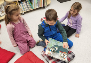 Dzieci oglądają książkę z przestrzennymi ilustracjami.