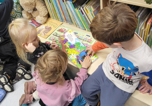 Dzieci oglądają książkę sensoryczną, z pokazanymi różnymi fakturami materiału.