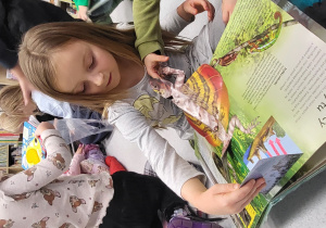 Dziewczynka ogląda książkę z przestrzennymi ilustracjami zwierząt..