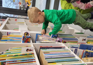 Chłopiec ogląda regały z książkami.