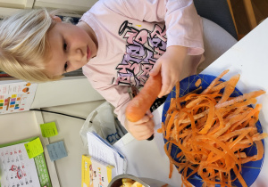 Dziewczynka obiera marchewkę.