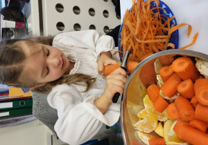 Dziewczynka obiera marchewkę.