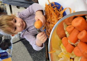 Dziewczynka obiera marchewkę.