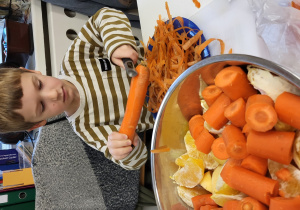 Chłopiec obiera marchewkę.