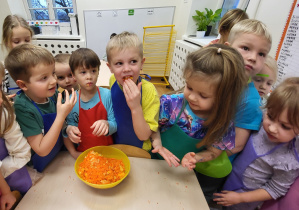 Dzieci wykonują sok z marchewki, jabłka i pomarańczy za pomocą sokowirówki sokowirówki.