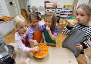 Dzieci wykonują sok z marchewki, jabłka i pomarańczy za pomocą sokowirówki sokowirówki.