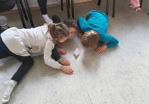 Troje dzieci dmuchając przesuwają łódkę z pieprzem.