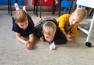 Troje dzieci dmuchając przesuwają łódkę z pieprzem.