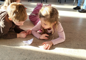 Dwoje dzieci dmuchając przesuwają łódkę z pieprzem.