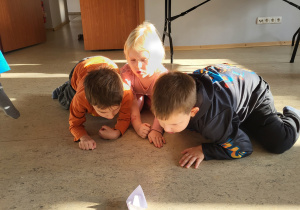 Troje dzieci dmuchając przesuwają łódkę z pieprzem.