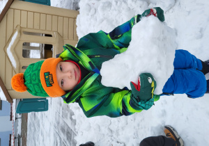 Chłopiec trzyma w rękach bryłę śniegu.