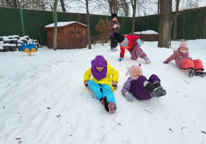 Dziewczynki zjeżdżają z górki.