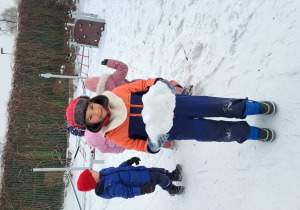 Chłopiec trzyma w rękach bryłę śniegu.