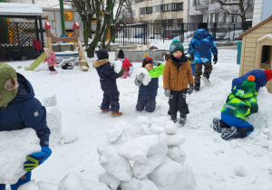Dzieci noszą śniegowe kule potrzebne do budowania igloo.