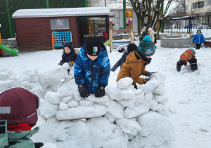 Dzieci budują igloo z brył śniegu.