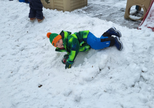 Chłopiec bawi się na śniegu.