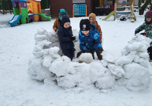 Dzieci budują igloo z brył śniegu.