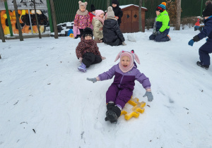 Dzieci zjeżdżają z górki.