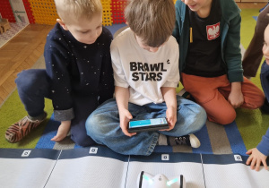 Chłopcy programują drogę robota na macie.