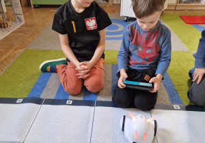 Chłopcy programują drogę robota na macie.