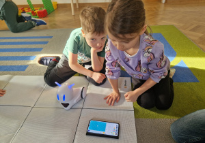 Dziewczynka uruchamia robota wg zaprogramowanej trasy.