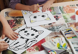 Dzieci wykonują pracę plastyczną - sylweta kota.