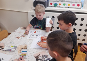 Chłopcy kolorują sylwetę kota.