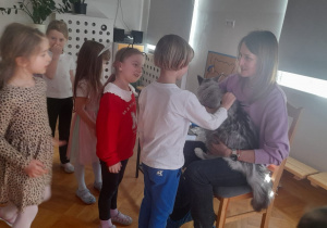 Dzieci uczestniczą w spotkaniu z kotem. Głaszczą go.