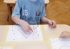 Chłopiec wykonuje eksperyment z kropkami farby na foli.