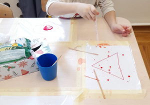 Chłopiec wykonuje eksperyment z kropkami farby na foli.