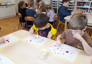 Dzieci wykonują eksperyment z " wędrującymi kropkami"