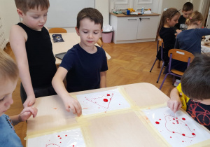 Dzieci wykonują eksperyment z " wędrującymi kropkami"