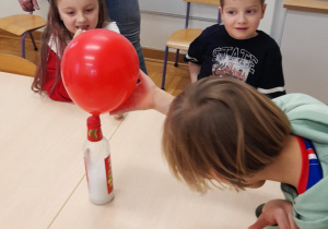 Dzieci wykonują eksperyment z balonem.