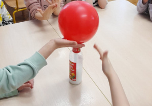 Dzieci wykonują eksperyment z balonem.