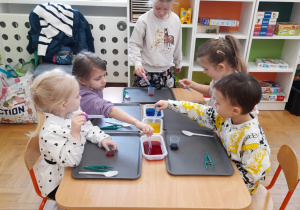 Dzieci barwią wodę na różne kolory.