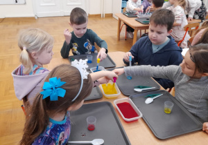 Dzieci barwią wodę na różne kolory.