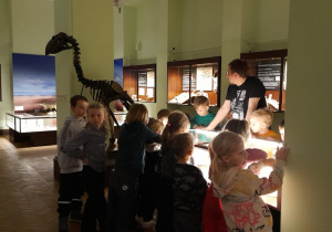 Dzieci oglądają eksponaty umieszczone w gablotach.