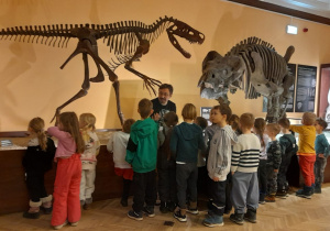 Dzieci oglądają szkielety dinozaurów.