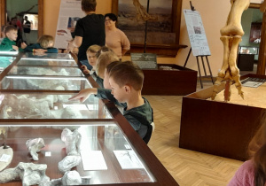 Dzieci oglądają eksponaty umieszczone w gablotach.
