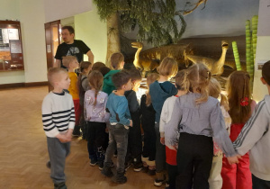 Dzieci oglądają makietę z dinozaurami.