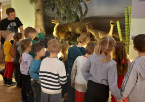 Dzieci oglądają makietę z dinozaurami.
