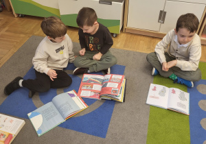 Dzieci oglądają książki z grupowej biblioteczki.