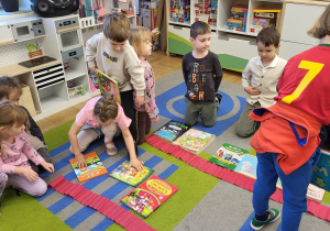 Dzieci układają na przygotowanych "półkach" z krepiny książki. Zadaniem jest ułożenie ich po 7 na półce - wprowadzenie cyfry 7.